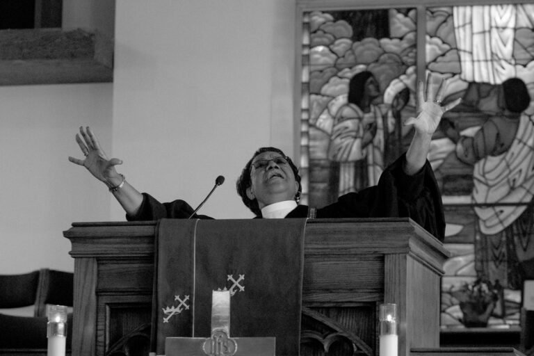 Joyous preacher with raised arms in church