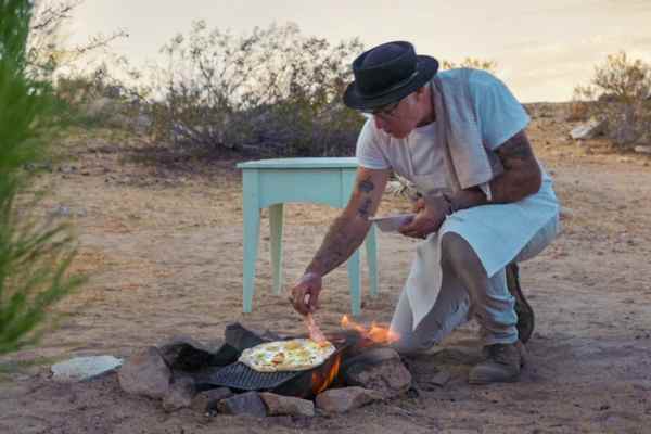 man cooking over campfile